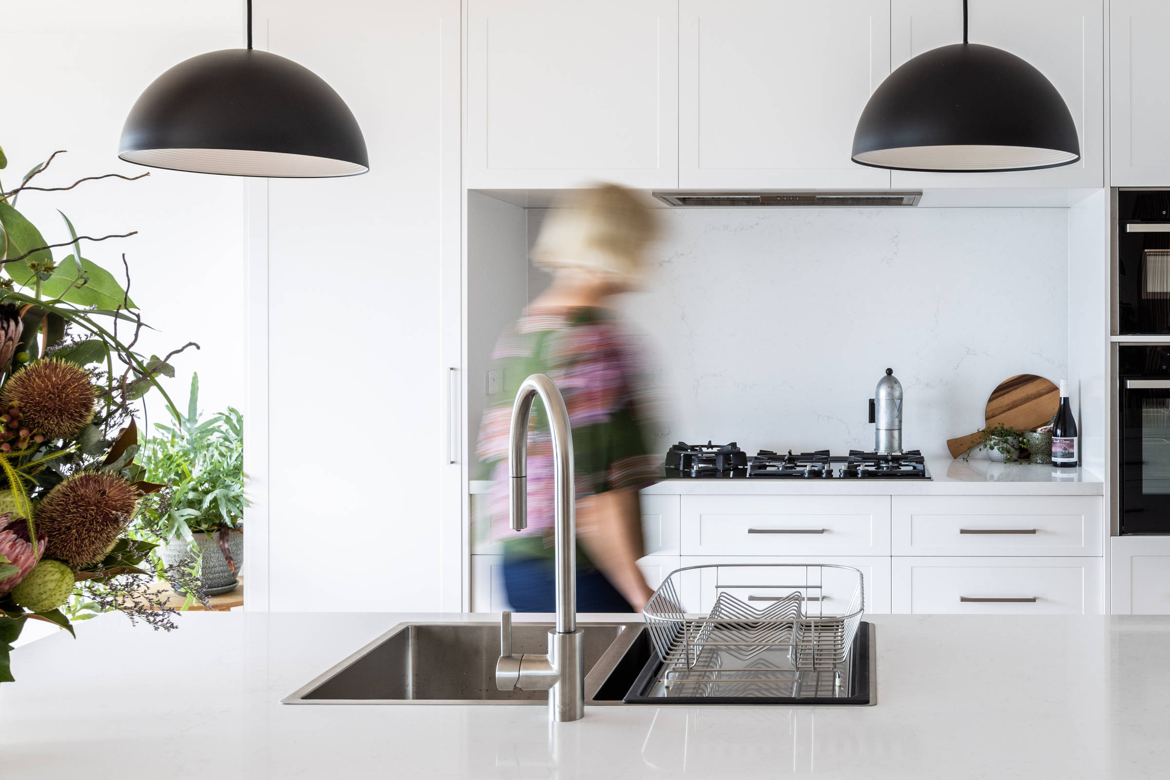 This light and bright, contemporary kitchen renovation has transformed this 1970s house. It features solid stone benchtops, pendant lighting, contemporary lighting, brushed chrome tapware and an in bench sink. Photo: Jordan Davis.