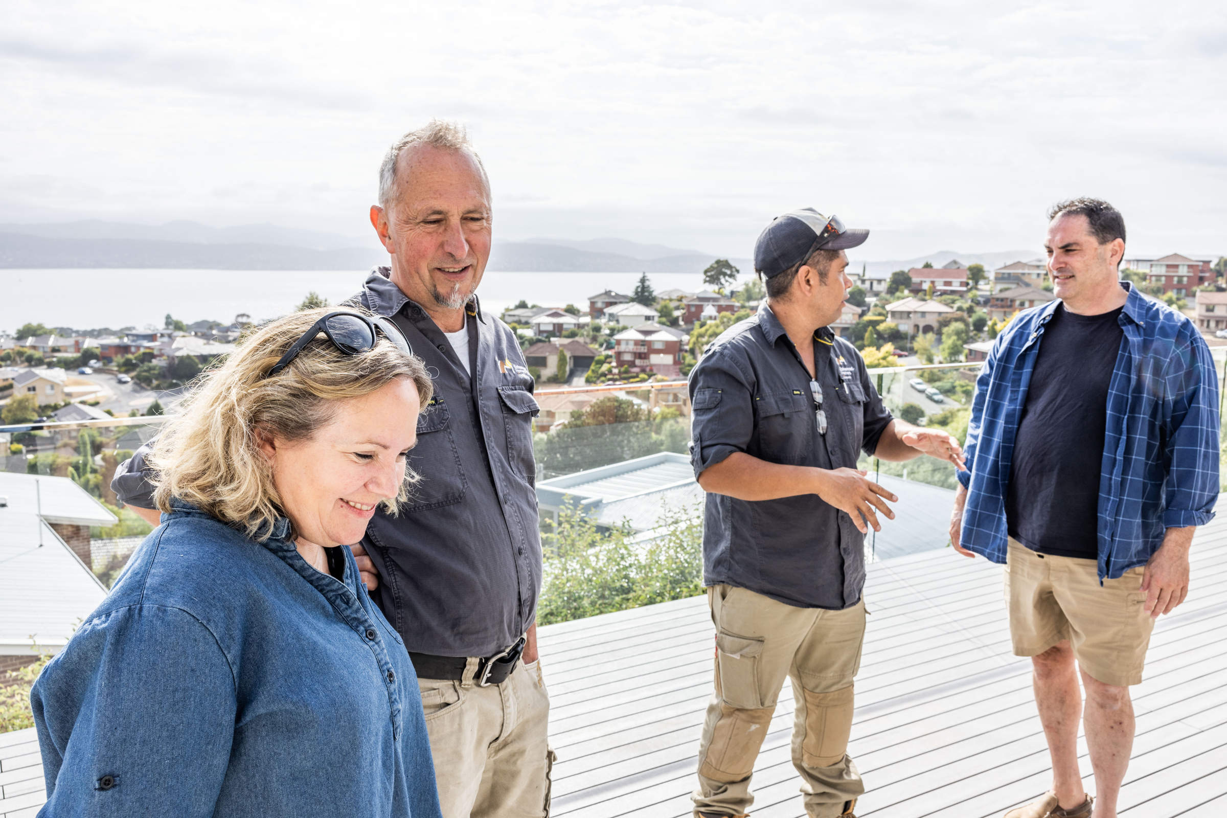 The Enhanced Construction team consulting with our clients about the renovation of their 1970s home, standing on their new deck with view of the River Derwent. Photo: Jordan Davis.